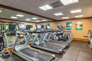 A gym with treadmills, stationary bikes, and a mirrored wall.