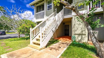 A two-story house with a front porch, a staircase, and a small garden area.