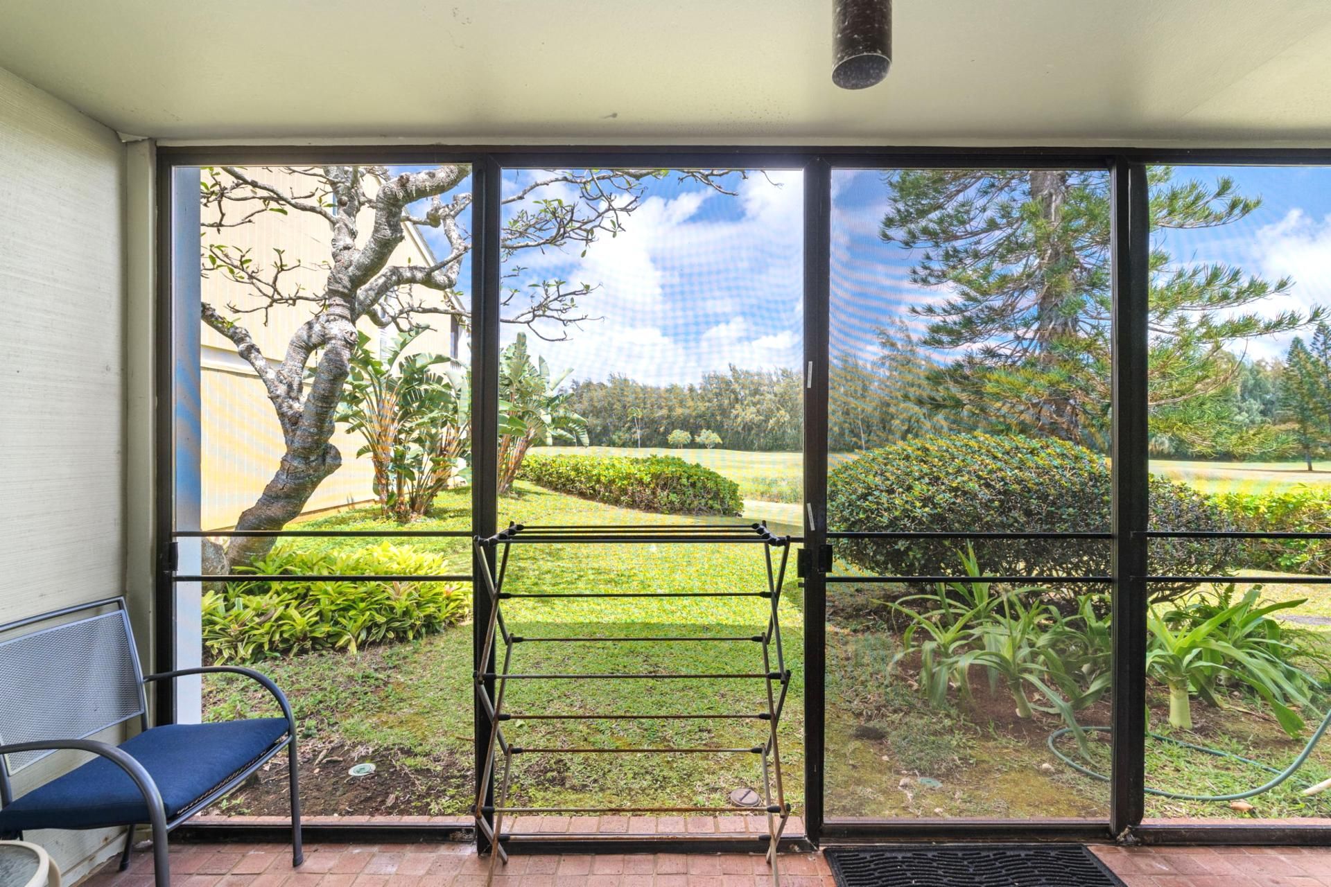 A room with a large sliding glass door leading to a garden with a bench and a chair.