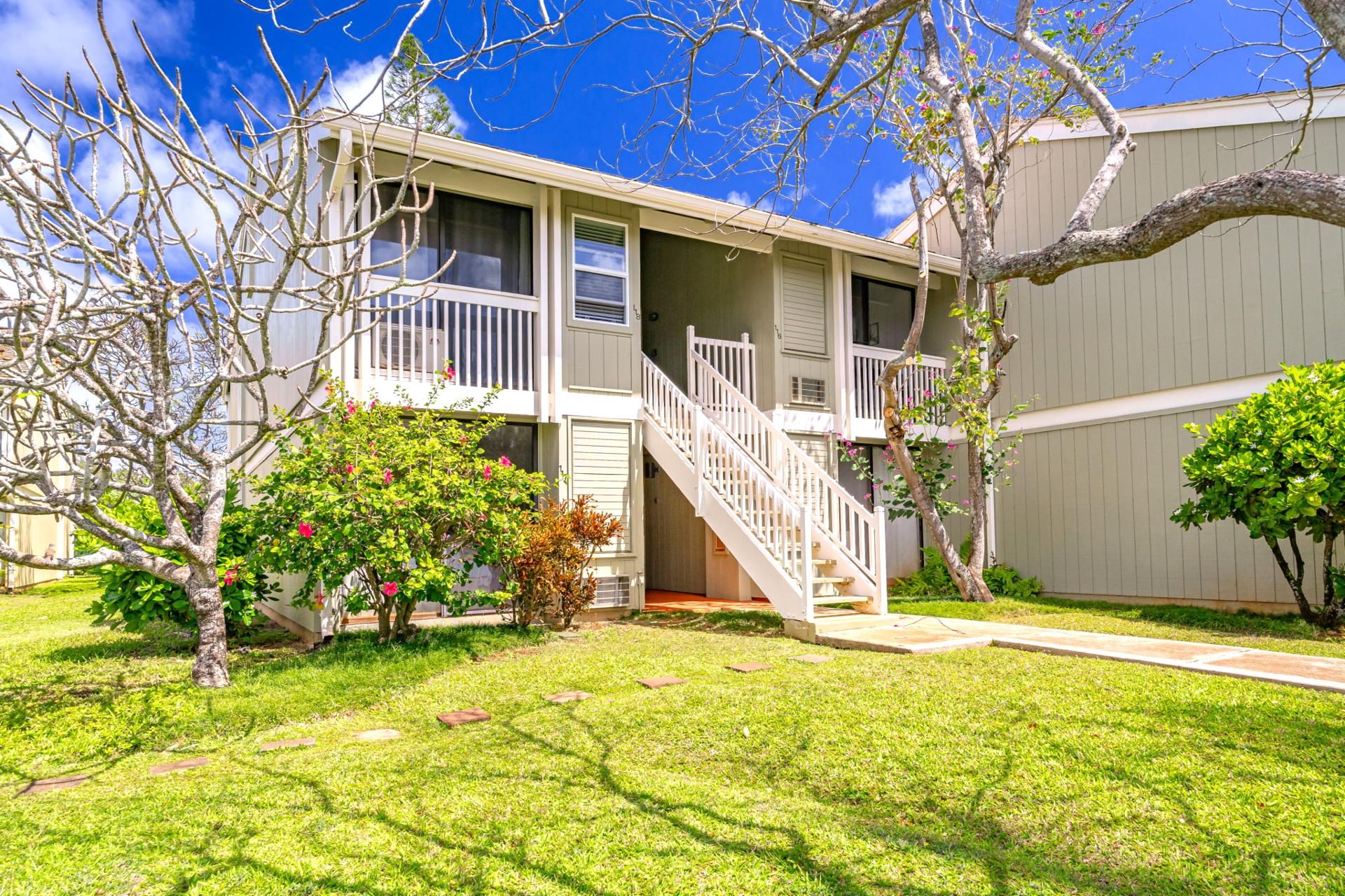 A two-story building with a central staircase, a small porch, and a well-maintained lawn.