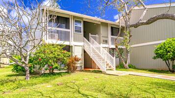 A two-story building with a central staircase, a small porch, and a well-maintained lawn.