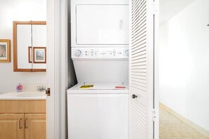 Ein Waschraum mit einer Frontlader-Waschmaschine, einem Waschbecken und Holzausbau.