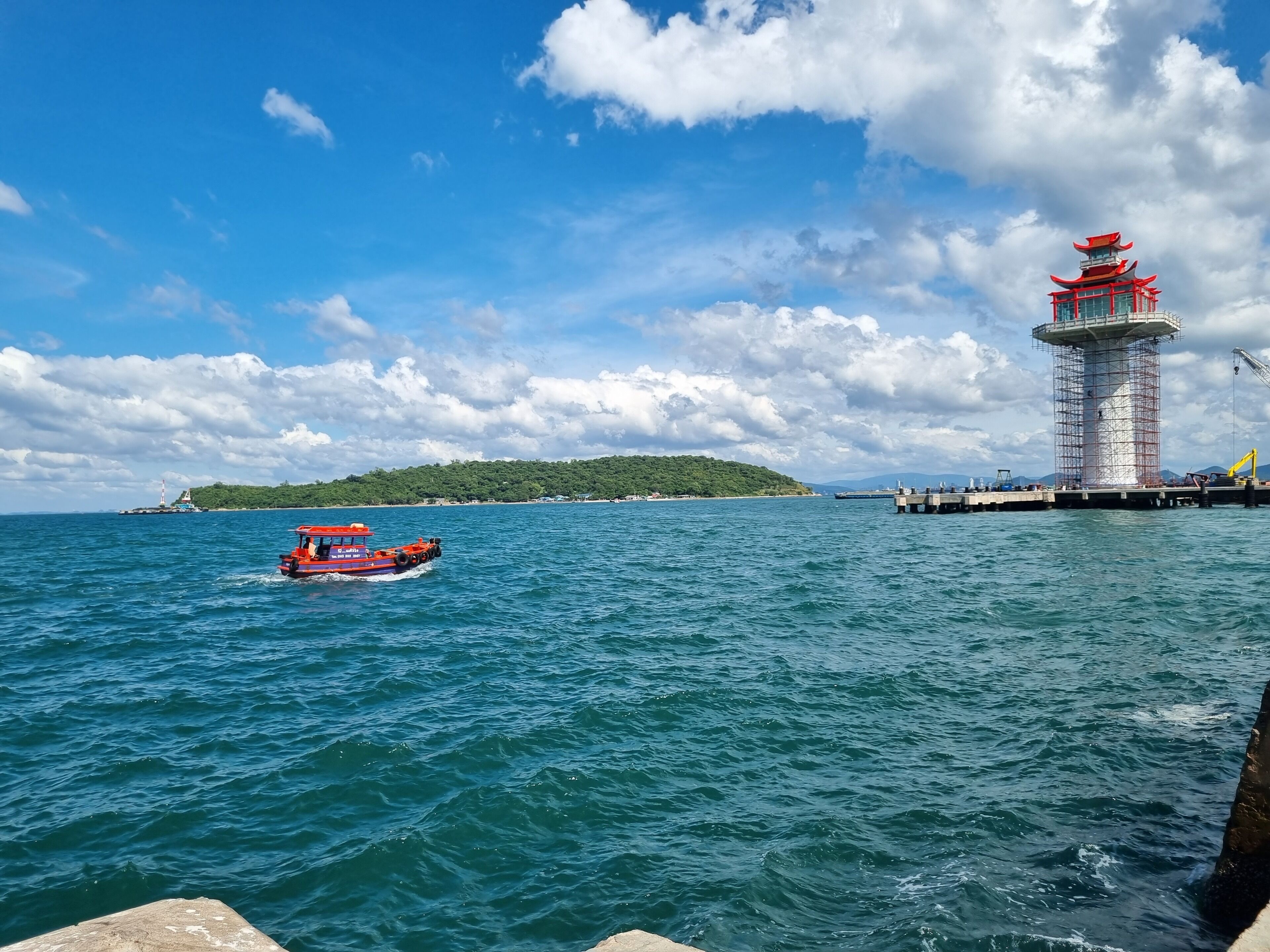 Escena costera con un faro, un barco y un muelle.