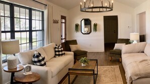 Una sala de estar con sofá, sillones, una mesa de centro, una lámpara y un reloj.