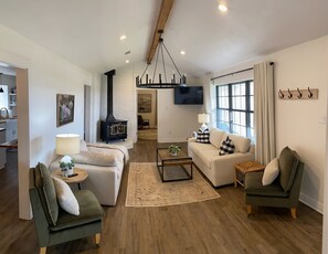 A modern living room with a fireplace, sofas, a coffee table, and a television. - Cozy Modern 2/2 Farmhouse Near Waco (Crawford)