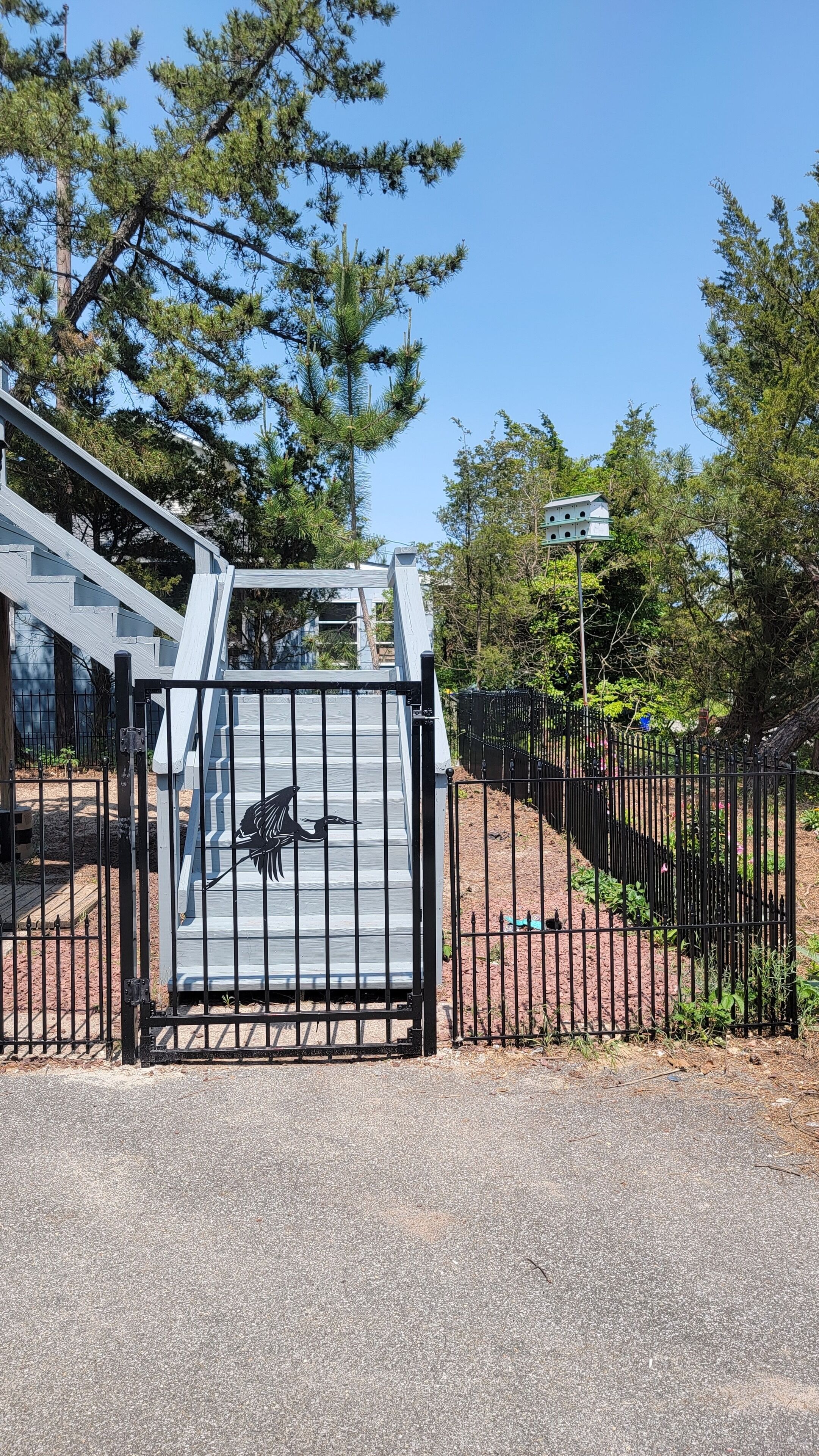 Une entrée fermée par un portail en métal et ornée d’une sculpture d’oiseau.