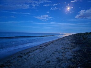 Une plage avec un ciel dégagé et le soleil se couchant ou se levant près de l’horizon.