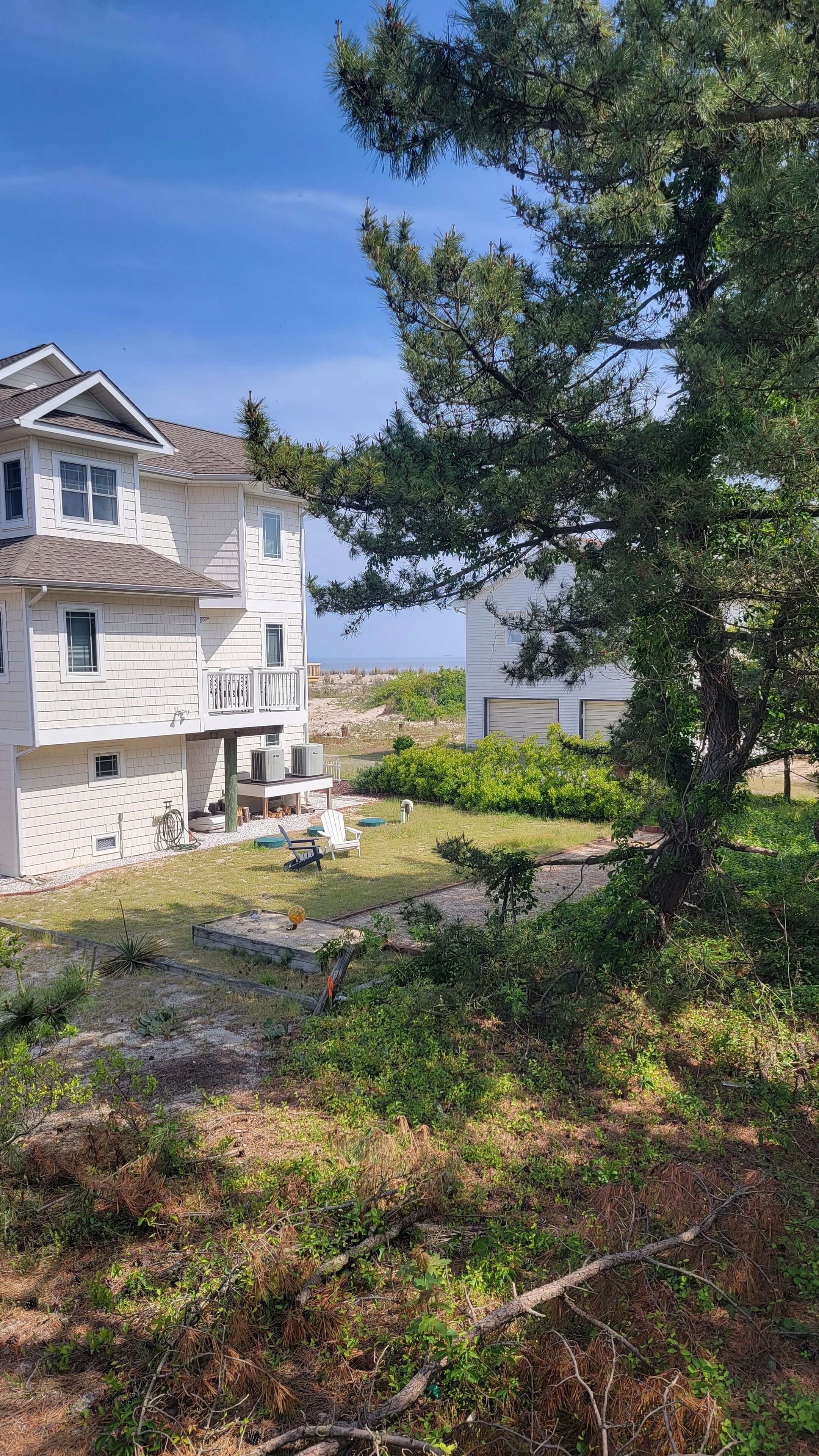 A two-story house with a balcony, a lawn, and a large tree in the foreground.