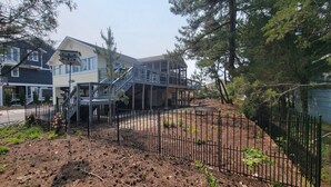 Ein zweistöckiges Haus mit überdachter Terrasse und einer Treppe, die zum oberen Stock führt.