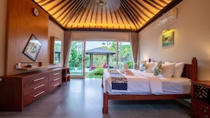 A spacious bedroom with a large bed, wooden ceiling, and a view of a garden and gazebo. - Luxury 3BR Kahuripan Villa (Bali)