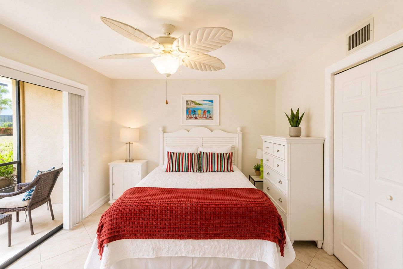 A bedroom with a bed, a ceiling fan, a nightstand, a chair, a dresser, and a door.