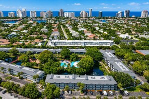 An aerial view of a resort area with multiple buildings, a central pool, and a marina. - Park Shore Resort-1stFloor BLDGJ#154 (Park Shore Resort)