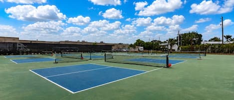 A tennis court with multiple courts, a net, and a clear sky.