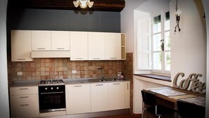 A kitchen with white cabinets, a gas stove, and a coffee bar. - Apartment in an old renovated mill with terrace (Capannori)