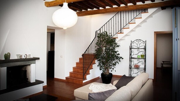 A modern living room with a staircase, a sofa, a potted plant, and a decorative shelf. - Apartment in an old renovated mill with terrace (Capannori)
