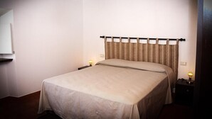 A neatly made bed with a headboard, two bedside lamps, and a wall-mounted mirror. - Apartment in an old renovated mill with terrace (Capannori)