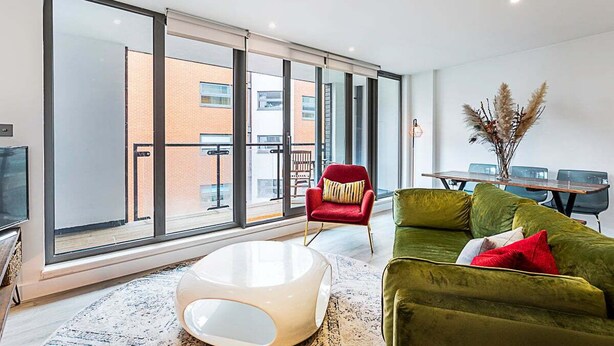 Un salon moderne avec un canapé vert, un fauteuil rouge et une table basse blanche.