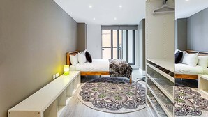 Une chambre moderne avec deux lits, une grande fenêtre et un tapis à motifs.