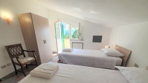 Et hotelværelse med to senge, et træskab, en stol og udsigt ud.