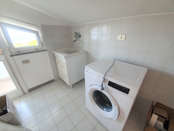 A laundry room with a washing machine, a sink, and a window. - “The Uncle Michele Penthouse” (Tropea)