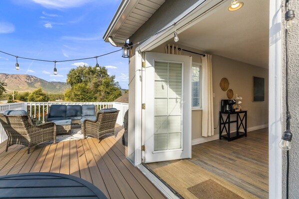 A deck with wicker furniture, a white door, and a view of mountains. - Serene Stay w/ Mountain Views in Downtown Monument (Monument)
