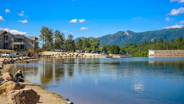 Una proprietà sul lago con una grande casa, un molo e montagne sullo sfondo.