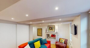 Relax in this stylish living room with a vibrant sofa, flat-screen TV, and cozy armchair.