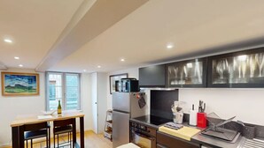 Una cucina moderna con zona pranzo, dotata di frigorifero, microonde, fornello e diversi utensili da cucina.