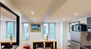 Enjoy meals in the central dining area with a wooden table and two chairs, offering a view of the outside.