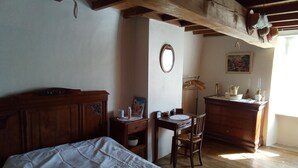 Ein Schlafzimmer mit einem hölzernen Bett, einem Schreibtisch mit Stuhl, einer Kommode und einem Spiegel an der Wand.