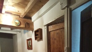 Ein Korridor mit Holzboden, einem Heizkörper, einer Holztür und einer Treppe.