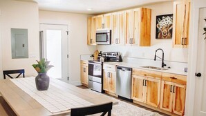 Une cuisine moderne dotée de meubles en bois, d’appareils électroménagers en acier inoxydable et d’un coin repas avec une table et des chaises.