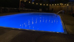 A swimming pool at night with string lights above.