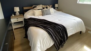 A bedroom with a large bed, a nightstand with a lamp, and a dresser.