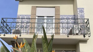 Un edificio con balcón, adornado con azulejos decorativos y un equipo de aire acondicionado Panasonic.