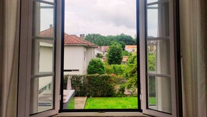 Una ventana abierta con vistas a un césped verde y casas a lo lejos.