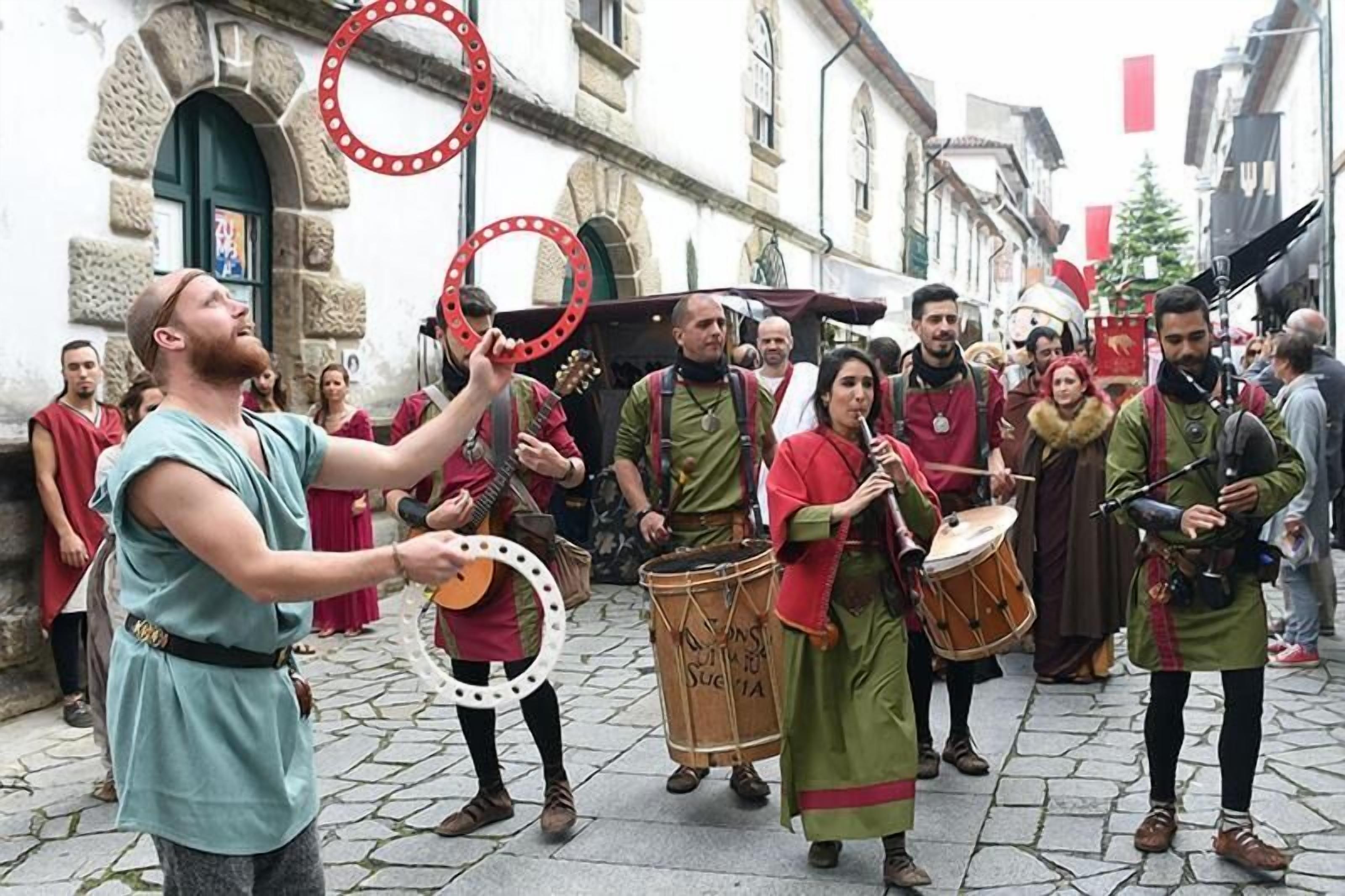 A group of people in historical costumes performing in a cobblestone street.