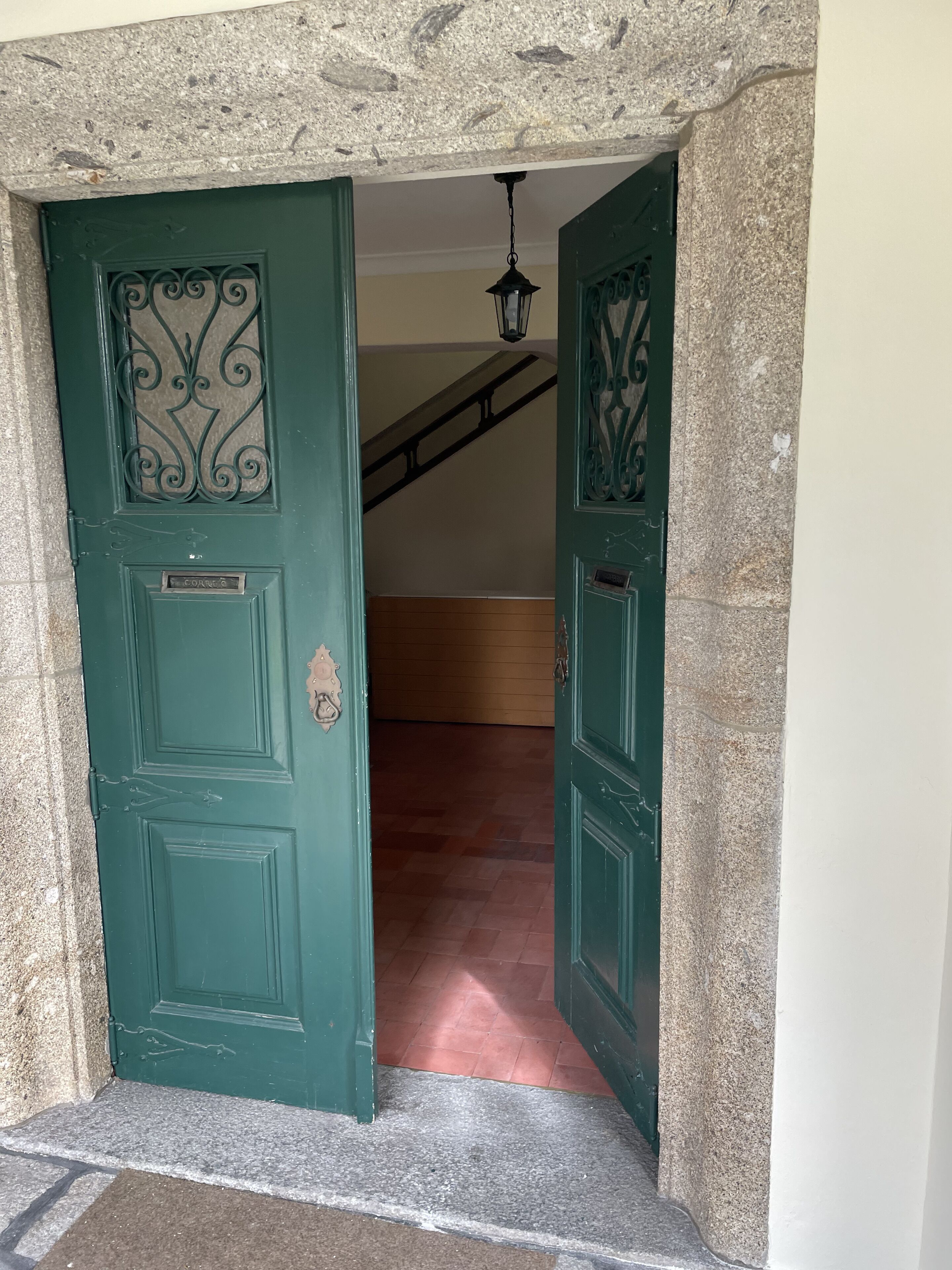 A green door with a decorative metal design, leading to a staircase.