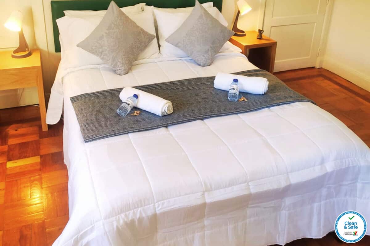 A neatly made bed with pillows, a blanket, and two water bottles.