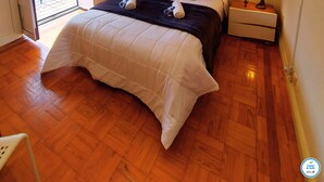 Un dormitorio con una cama, dos mesitas de noche, un televisor y una ventana con persianas.