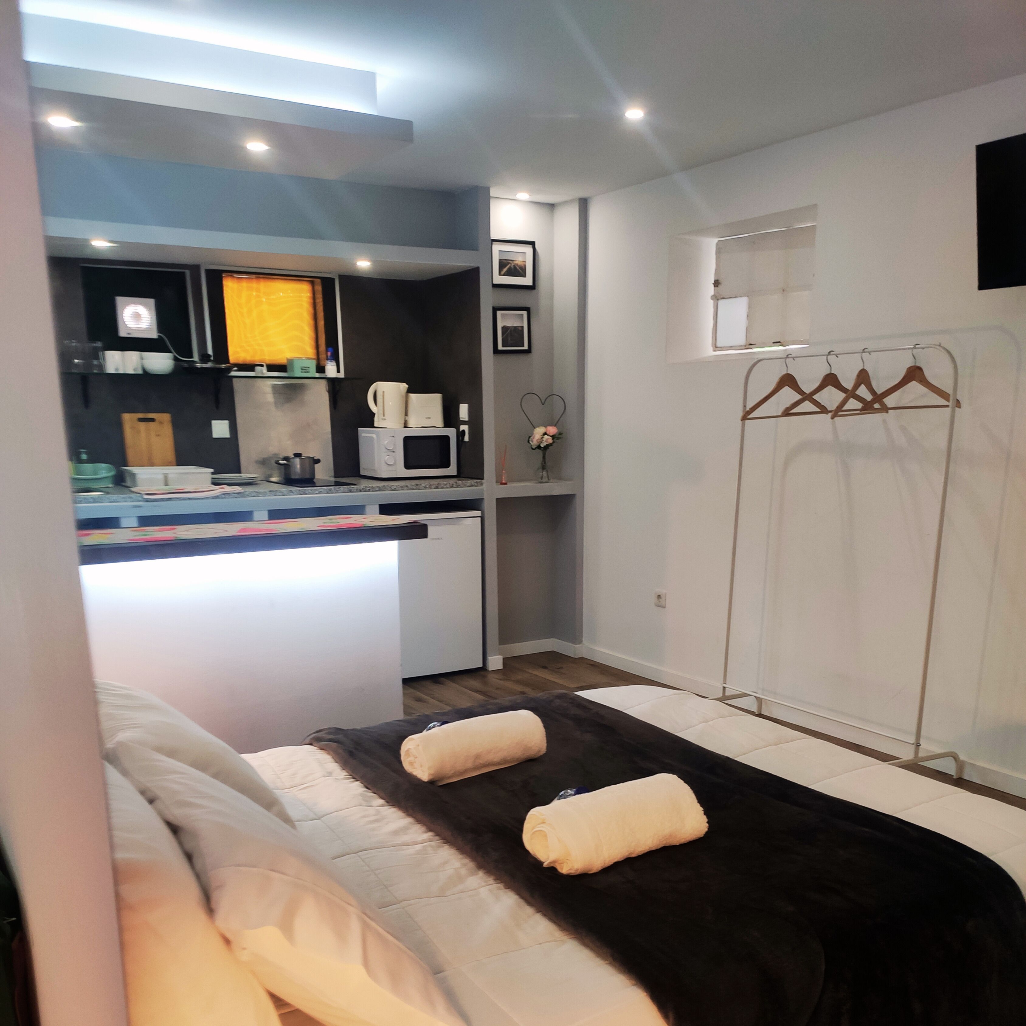 A modern hotel room with a bed, a small kitchenette, and a walk-in closet.