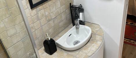 A bathroom with a white sink, a mirror, and a green towel hanging on the wall.