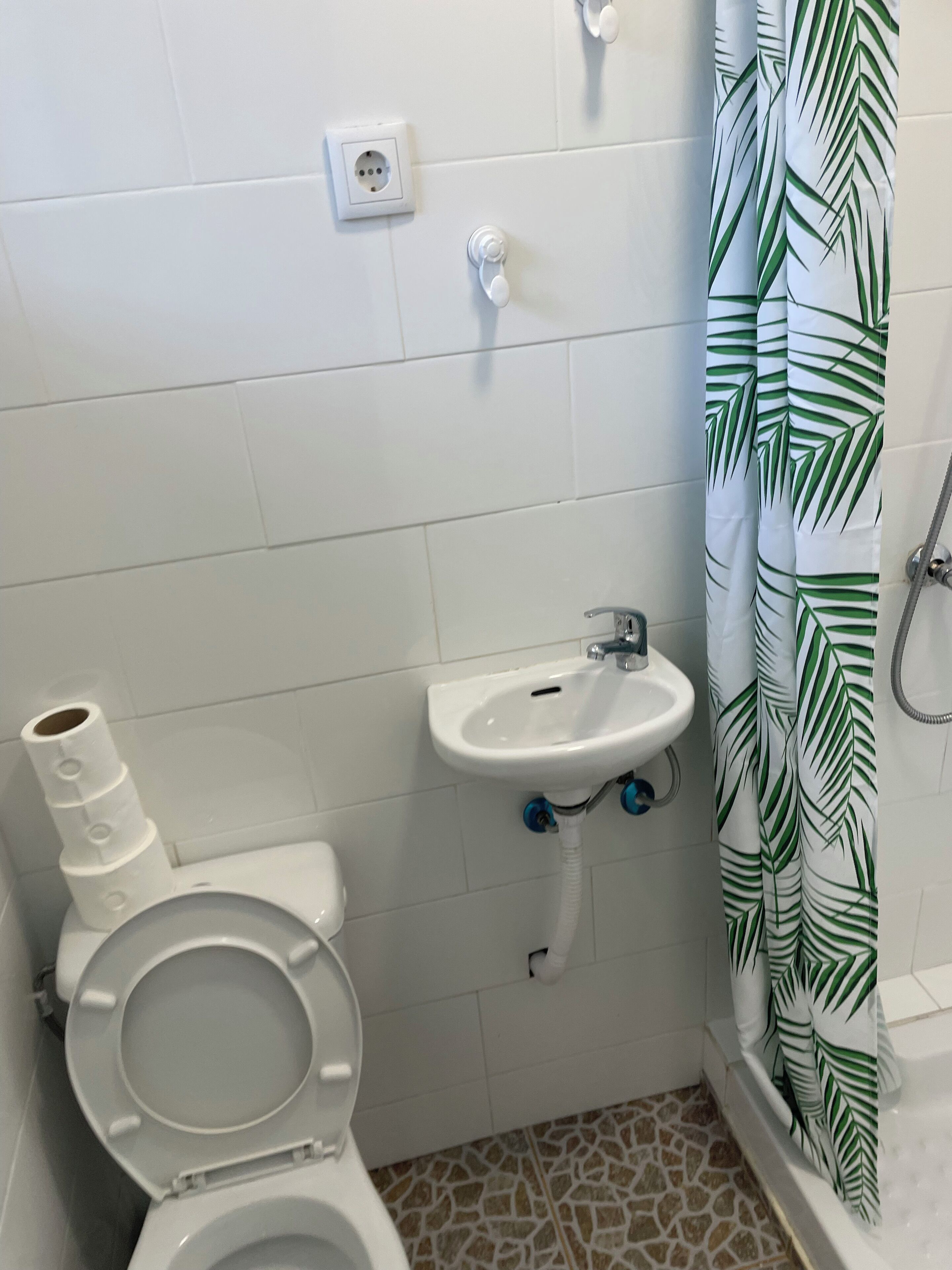 Un baño con inodoro, lavamanos y cortina de ducha.