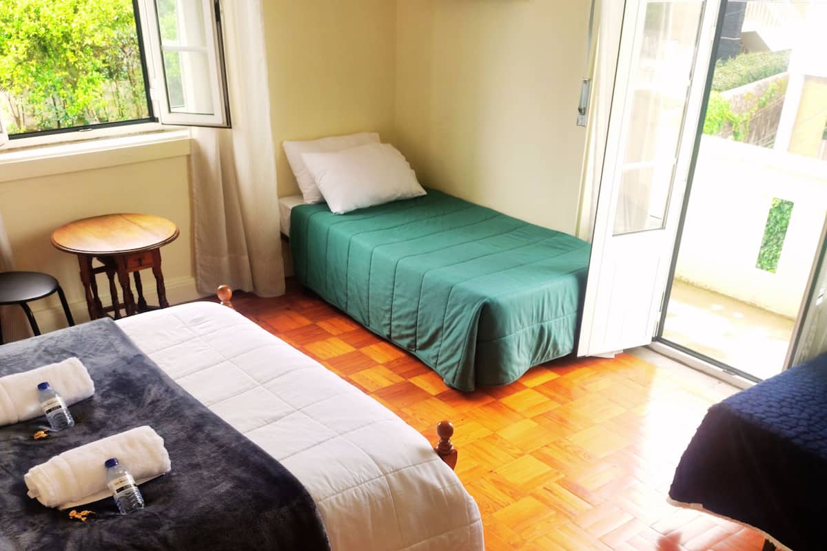 A room with two beds, a small table, and a TV on the wall.