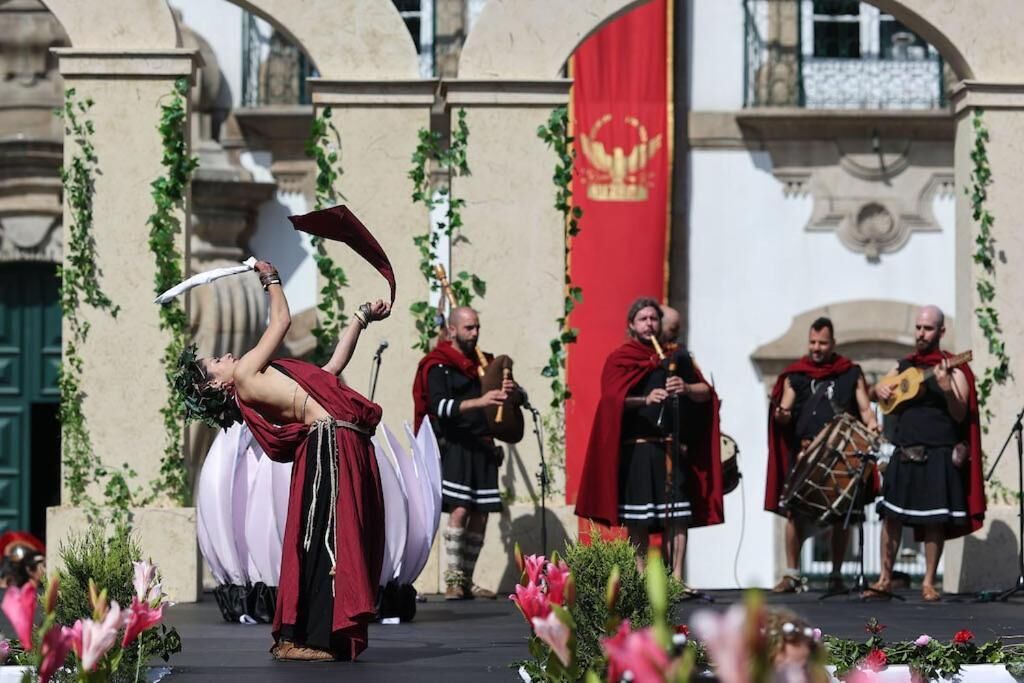 A person performing an act with a sword on a stage, surrounded by musicians and a red flag.