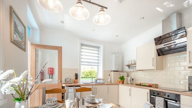 A modern kitchen with white cabinets, a black oven, and a dining area with a wooden table and chairs.