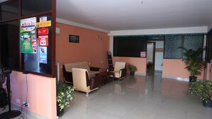 A hotel reception area with a reception desk, seating area, and a signboard with hotel information. - Transit Bay  (Rajahmundry)