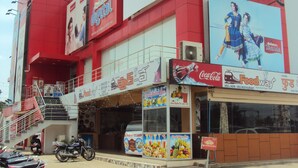 A multi-story building with various commercial establishments including a food court, a Coca-Cola outlet, and a Reliance Digital advertisement. - Transit Bay  (Rajahmundry)