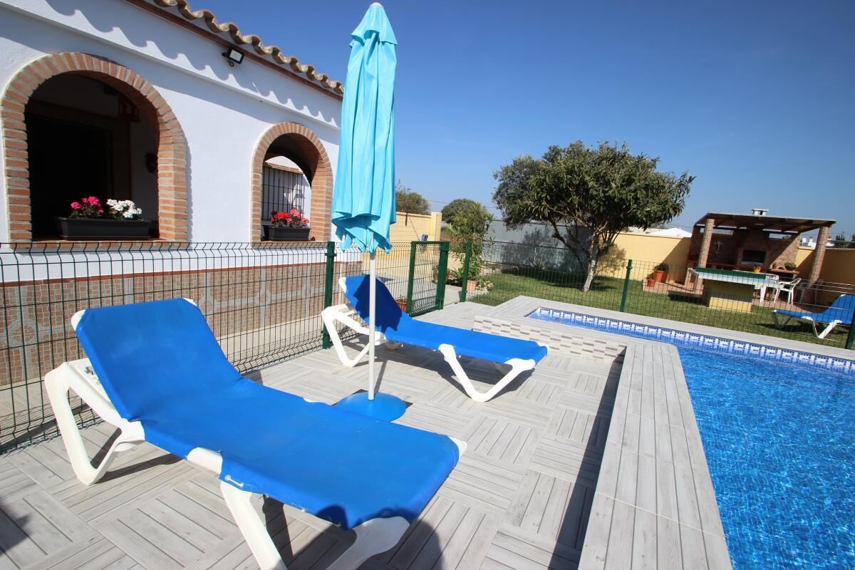 A poolside area with lounge chairs and a blue umbrella.