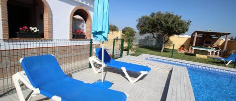 A poolside area with lounge chairs and a blue umbrella.